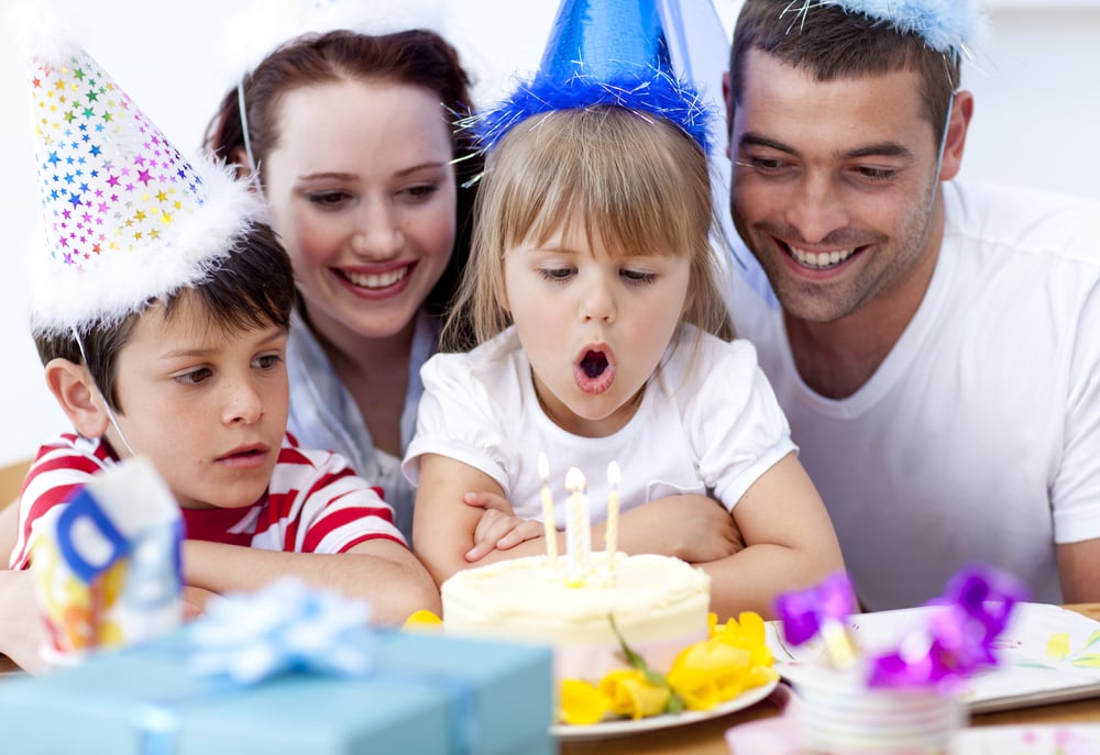 Little girl blowing out candles in her birthday with her family